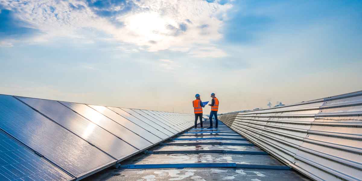 Two technicians in distance discussing between long rows of photovoltaic panels.